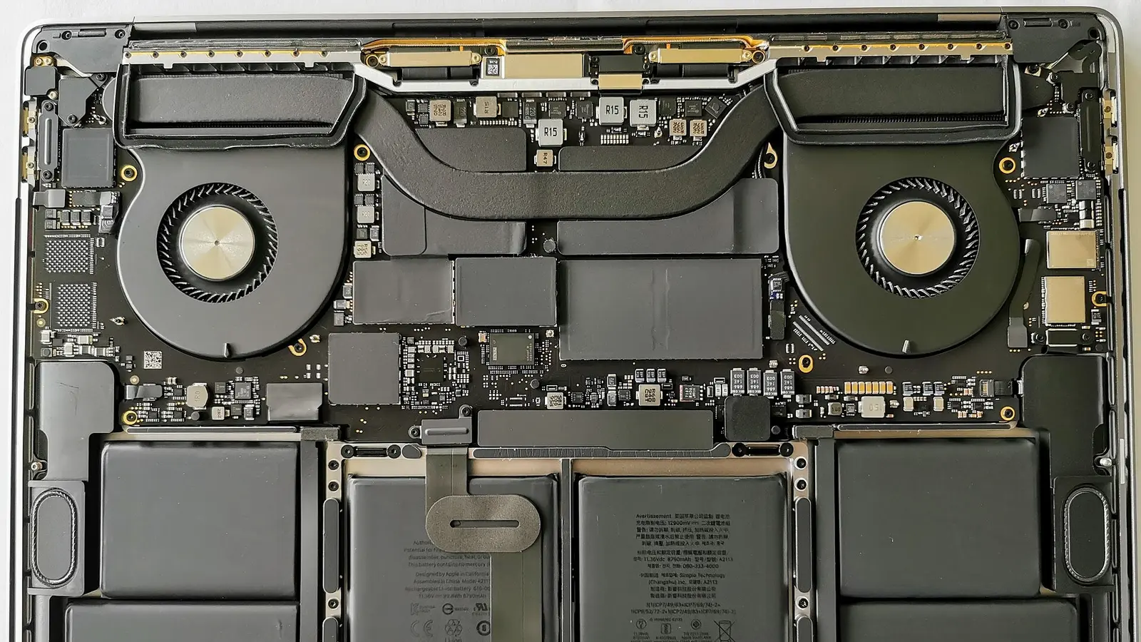 Opened laptop interior with twin fans, battery cells and circuit boards visible
