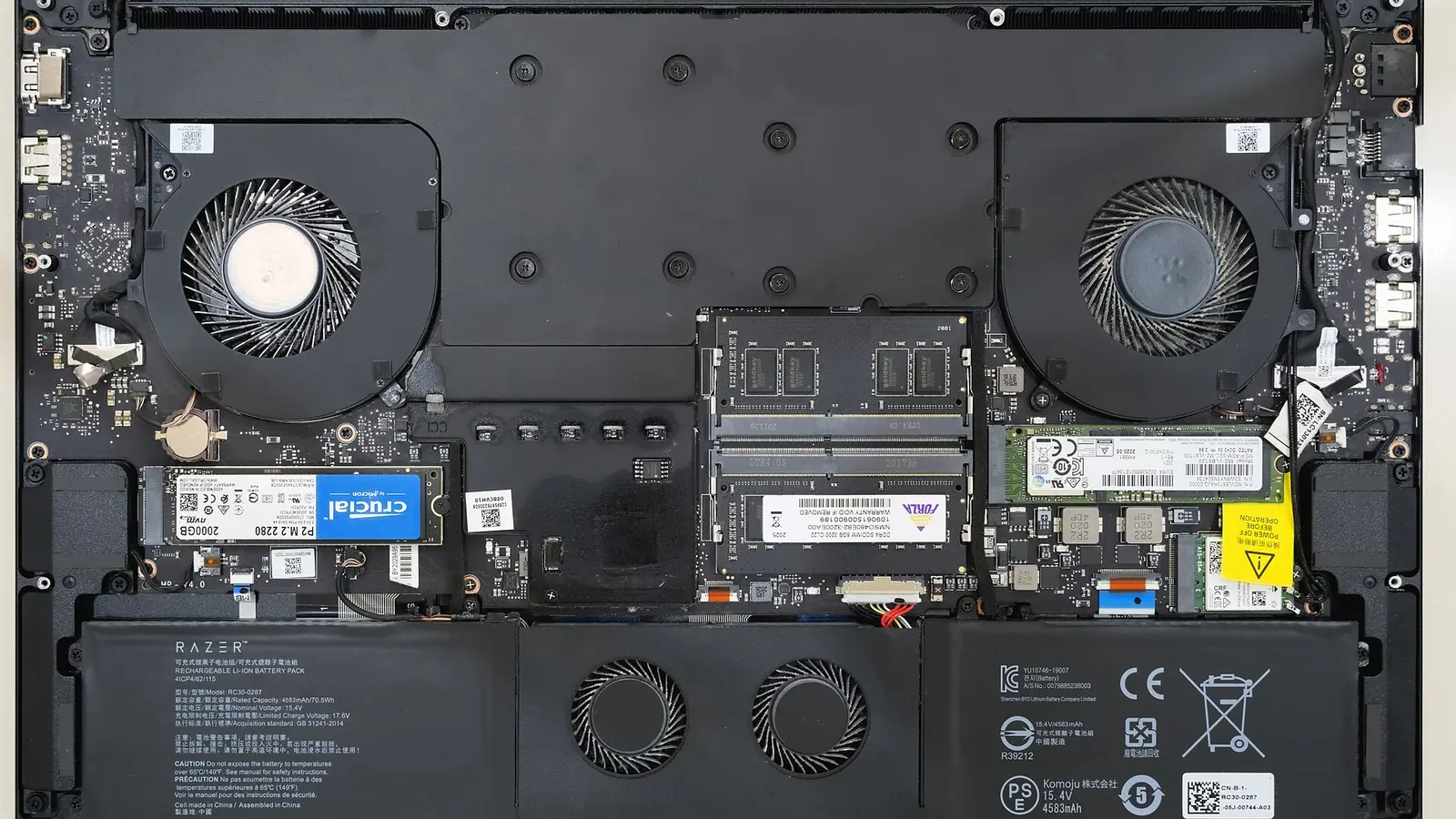 Opened Razer laptop with internal battery pack, fans, RAM and SSDs visible